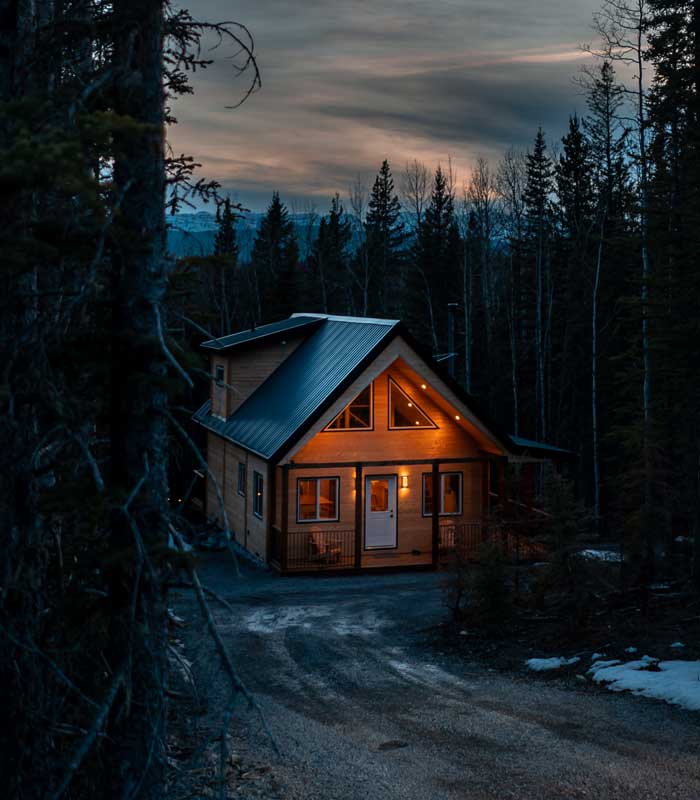 lit exterior of cabin in the woods